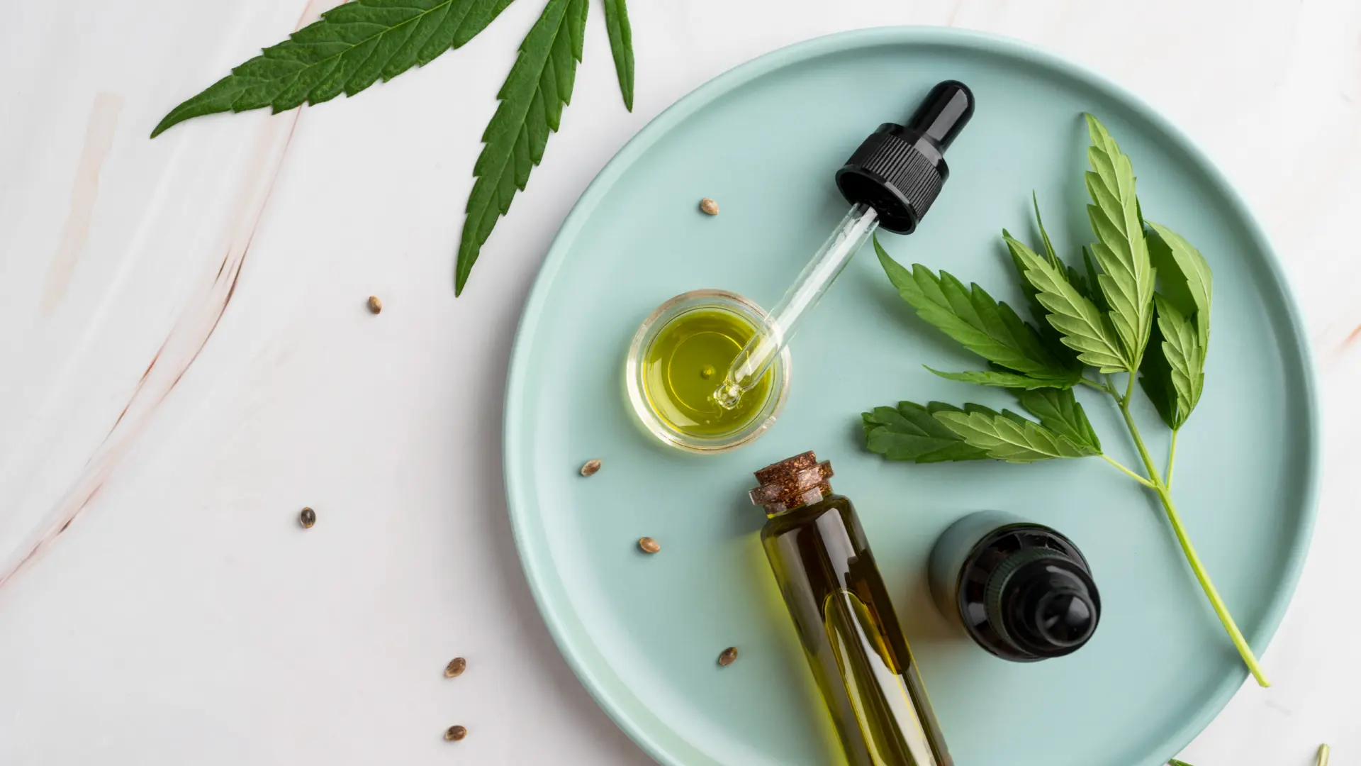 Some cannabis leaves on a white background with some seeds and alternative medicine